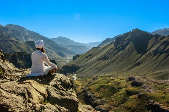 a person sitting on a person sitting on a rock looking out over a valley